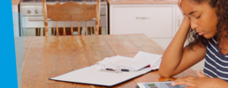 Learner at a table studying with a hand pressed against head.