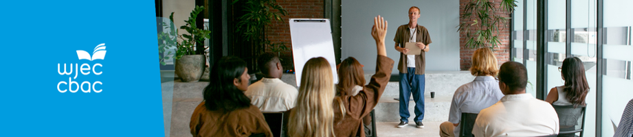 Man presenting at a learning seminar with participants hands raised. 