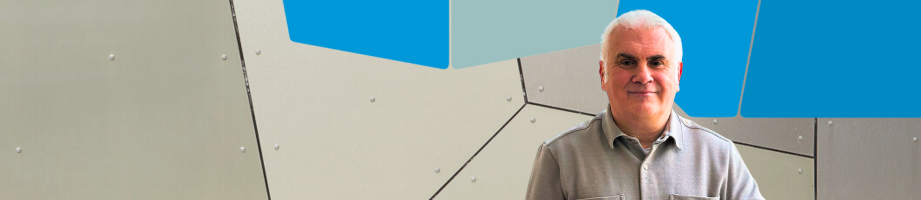 Headshot of rep header Rhys Huws in front of a modern geometric wall